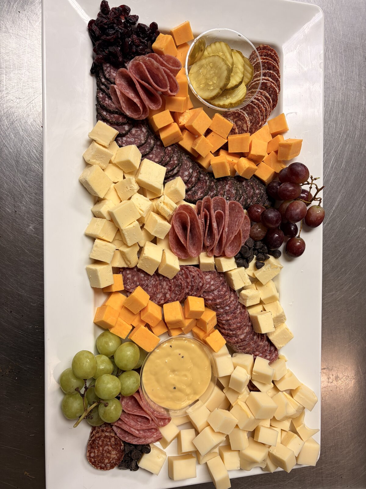 Long charcuterie board with cheeses, meats and grapes